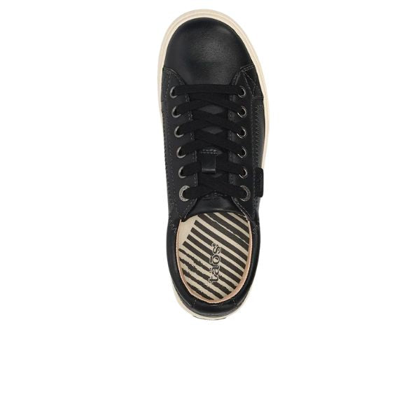 The TAOS Womens Plim Soul Lux Black is a black sneaker with black laces, a white sole, and a diagonally striped tan and black insole featuring metatarsal support and the TAOS brand name. Seen from above.