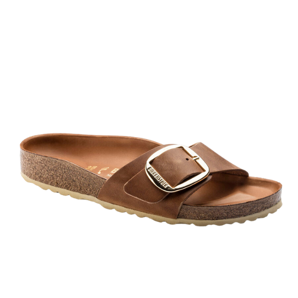 The Birkenstock Womens Madrid Big Buckle Cognac sandal features a Wide brown leather strap, large gold buckle, supportive cork footbed, and a textured sole for added grip.