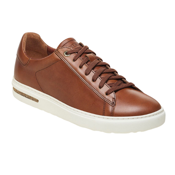 The Birkenstock Mens Bend Low Cognac by BIRKENSTOCK is a brown natural leather low-top sneaker with brown laces, a white rubber sole, minimal stitching, and a contoured footbed for classic Birkenstock support.