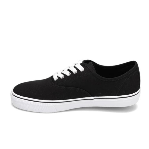 The Rival Women’s Trips Black/White sneaker by RIVAL, INC. features a black canvas upper, white laces, and a white rubber sole with a cushioned Rival+ footbed for all-day comfort, shown in profile on a plain white background.