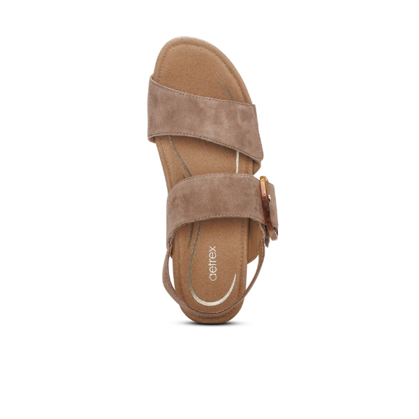 The Aetrex Womens Ashley Espadrille Wedge Taupe by AETREX WORLDWide INC features brown suede, two Wide straps, a slingback heel strap with side buckle, and cushioned arch support, displayed on a white background.