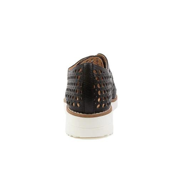 A rear view of the Django & Juliette Womens Onstage Black Leather shoe by DJANGO & JULIETT, featuring black perforated leather, a white sole, and brown trim, blends athleisure chic style with foot pain relief against a white background.