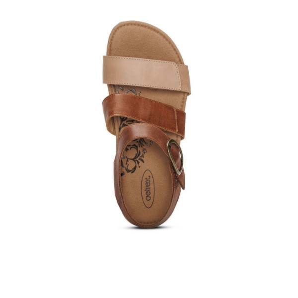 The Aetrex Womens Lilly Adjustable Quarter Strap Sandal in Walnut by AETREX WORLDWide INC features tan and brown leather straps, an open toe, floral insole pattern, a circular metal side buckle, and a Memory Foam Footbed, seen from above on a white background.