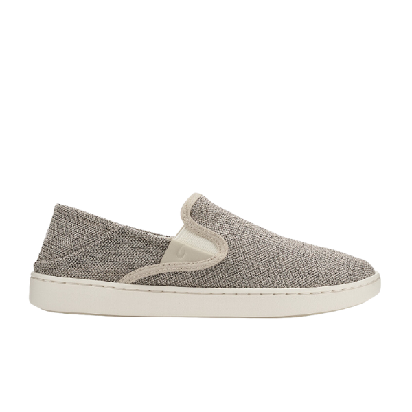 The OLUKAI Womens Tape Pehuea is a slip-on shoe with a textured light gray upper, white elastic sides, and a white rubber sole. It features an anatomical footbed and Drop-In Heel, shown side view on a plain white background.