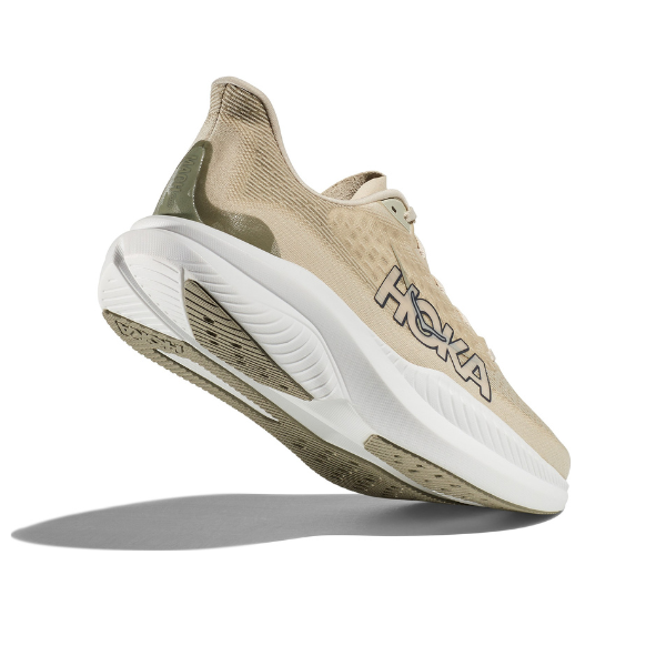 The HOKA Mens Mach 6 (Medium Width) in Beige/Oatmilk Barley appears midair with white and olive green accents, showcasing its thick cushioned sole—ideal for everyday running and helping reduce foot pain.