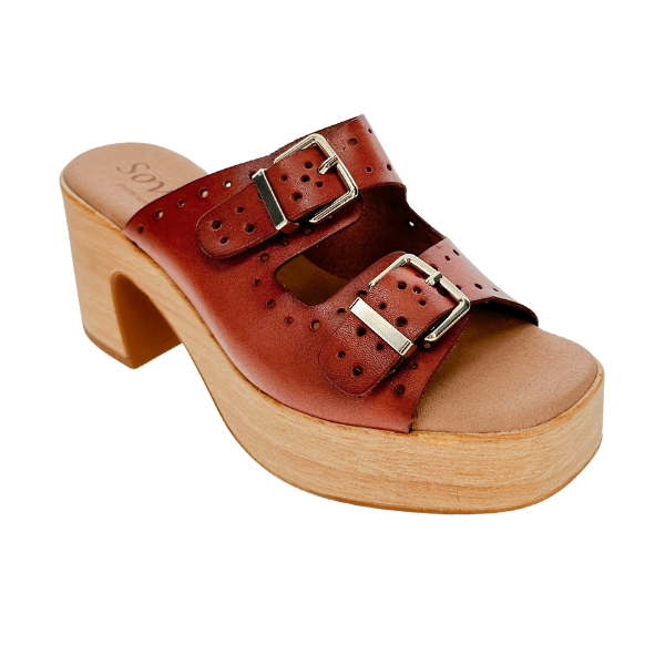 The SOVELLA Womens Paola Brown clog sandal features two silver buckles, perforated detailing, a chunky wooden platform heel, open toe design, and a supportive footbed for comfort.