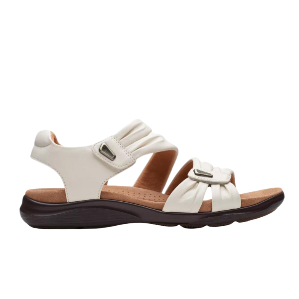 The Clarks Womens Wide Kitly Ave White sandal features adjustable straps, a Contour Cushion footbed, and a dark brown low wedge sole for all-day comfort and casual style.