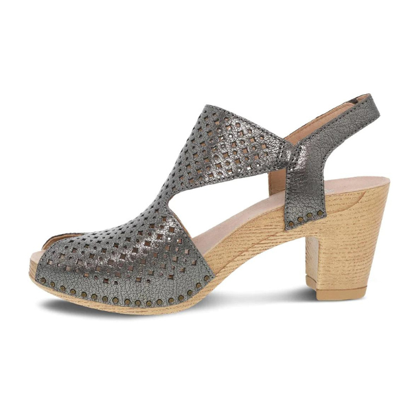 The Dansko Womens Teagan Gunmetal by DANSKO is a metallic silver slingback sandal with cut-outs, open toe, wooden block heel, studded sole accents, and small perforations for breathability and added foot pain relief.