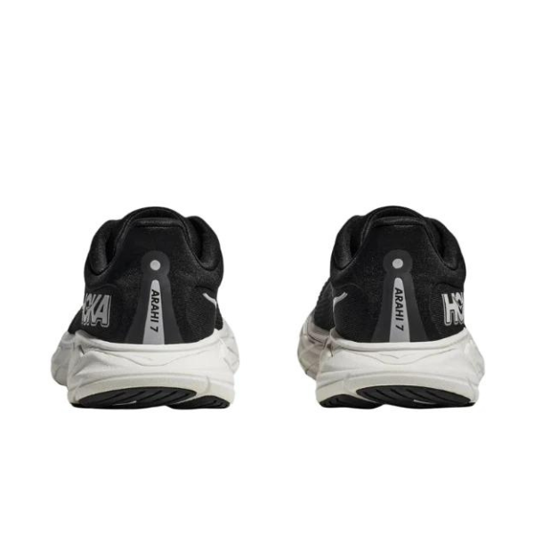 The HOKA Mens Arahi 7 Wide Black/White stability shoes are shown from the back, featuring the HOKA logo, model name on the heels, and innovative J-Frame technology.