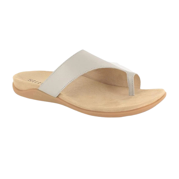The STRIVE Womens Capri III Latte is a beige and tan open-toe thong sandal with a Wide, smooth strap, a flat contoured sole, and BFT Technology for superior orthotic comfort.