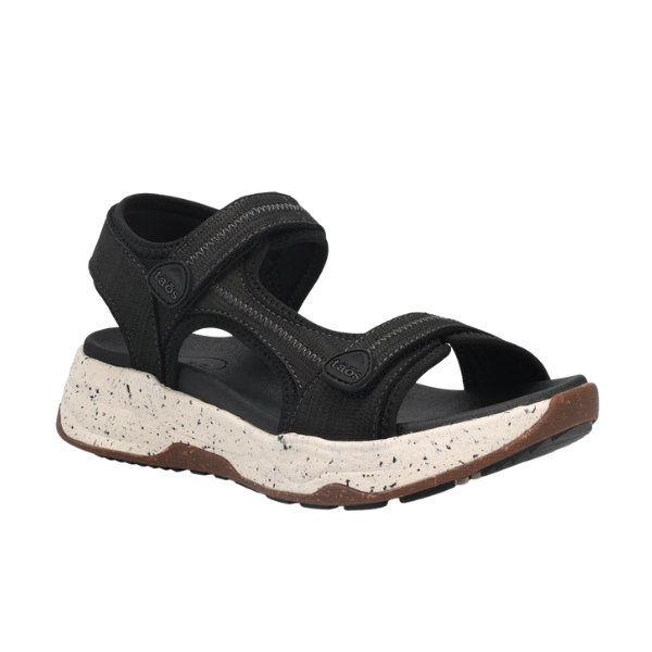 The TAOS Taos Womens Super Side Black sandal features adjustable straps, a black open-toe design, a white speckled thick sole, and a brown textured all-terrain rubber outsole.
