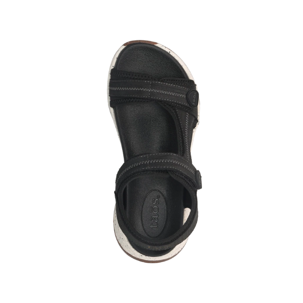 Top view of the Taos Womens Super Side Black sandal by TAOS: black open-toe, two adjustable straps, visible stitching, anatomical Structured Support footbed, white and brown sole, and TAOS branding embossed on the footbed.