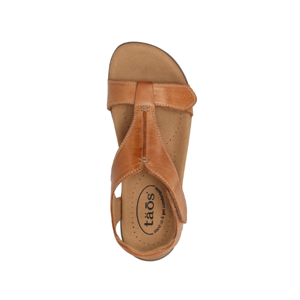 The TAOS Womens The Show Caramel sandal features tan leather, an open toe, ankle strap, and cushioned arch-support insole with the TAOS logo. Shown from above on a white background.