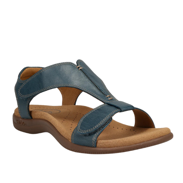 The Taos Womens The Show Petrol Blue sandal by TAOS features blue leather, open toe, adjustable Velcro straps, a tan cushioned sole with built-in arch support—ideal for comfort and everyday wear.