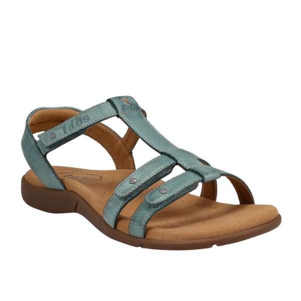 The Taos Womens Trophy 2 Teal sandal by TAOS features teal leather, a cushioned tan footbed, brown sole, metal studs, and enhanced arch support for comfort and relief from foot pain—perfect for casual wear.