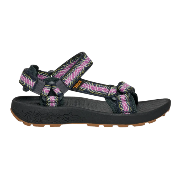The Teva Womens Hydratrek Sandal in Black/Purple features quick-dry purple, pink, and white webbing straps, adjustable hook-and-loop closures, a textured black sole, and a brown recycled Spider Rubber outsole.