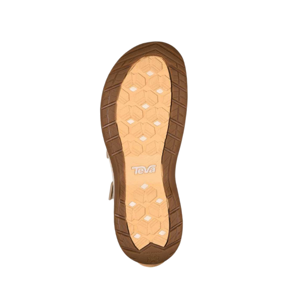 The image shows the sole of the Teva Womens Tirra CT Birch sandal, featuring a tan and brown honeycomb-patterned tread and Teva logo at the center for enhanced traction and durability, ideal for active lifestyles.