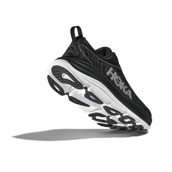 A side and slightly low-angle view of the HOKA Mens Gaviota 5 (Medium Width) in Black/White, showcasing its stabilizing H-Frame technology and visible sole, with a shadow cast on a white background.