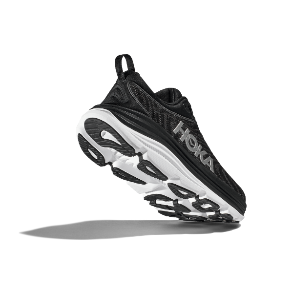 The HOKA Womens Gaviota 5 Wide Black/White running shoe floats above a white background, angled to display its sole, signature side logo, and stabilizing H-Frame technology while casting a shadow below.