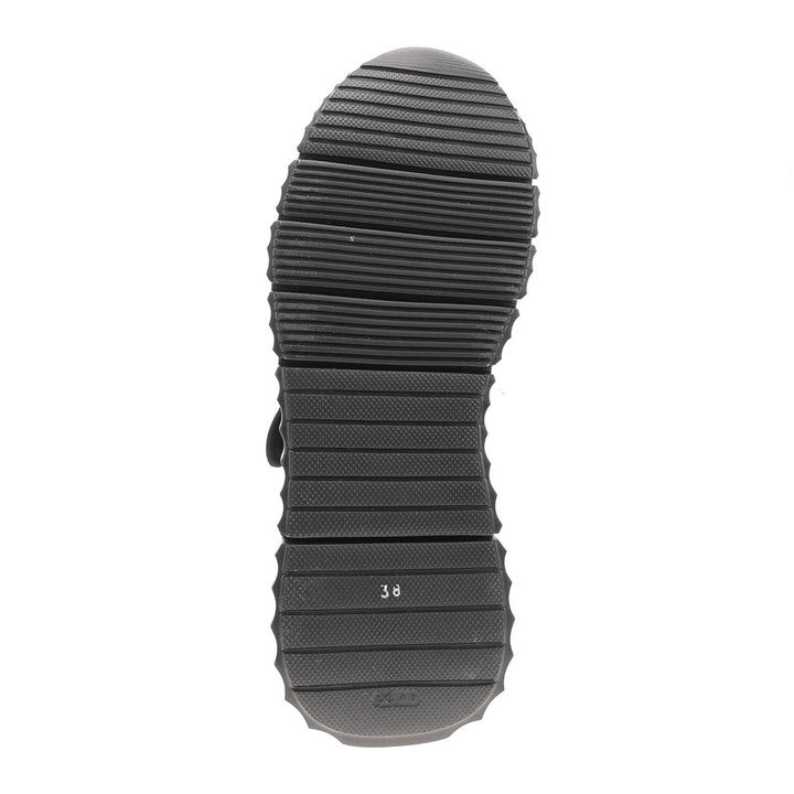 The image shows the black ridged sole of the SOVELLA Sovella Womens Jessica Black Camo Mary Jane shoe, viewed from below. Horizontal grooves and a size 38 marking are visible near the center, highlighting its lightweight design.