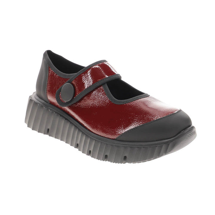 A single SOVELLA Womens Jessica Red Mary Jane shoe features a shiny burgundy upper, black toe and trim, thick ridged black sole, and a strap with a large black button.