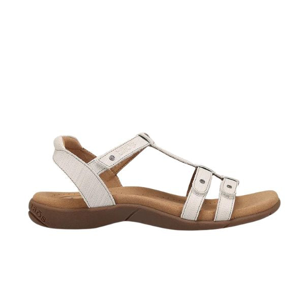 The TAOS Taos Womens Trophy 2 Icee is a white strappy leather sandal with an open toe, cushioned tan footbed, and brown sole. It offers arch and metatarsal support for comfort and relief from foot pain during casual wear.