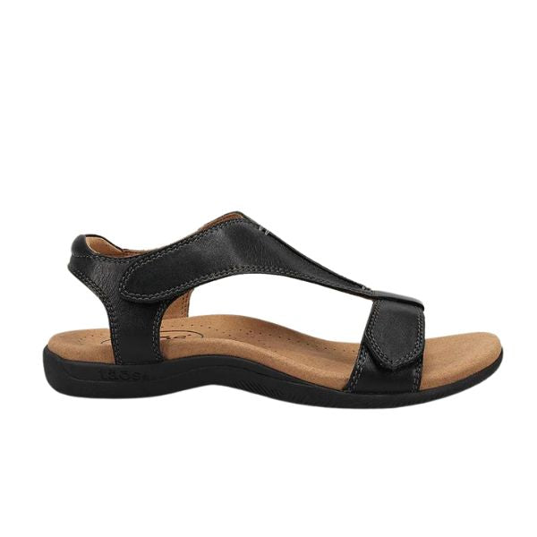The TAOS Taos Womens The Show Black is a black leather sandal featuring a low heel, adjustable ankle strap, T-strap design, and cushioned tan insole with a contoured black sole for arch support and all-day comfort.