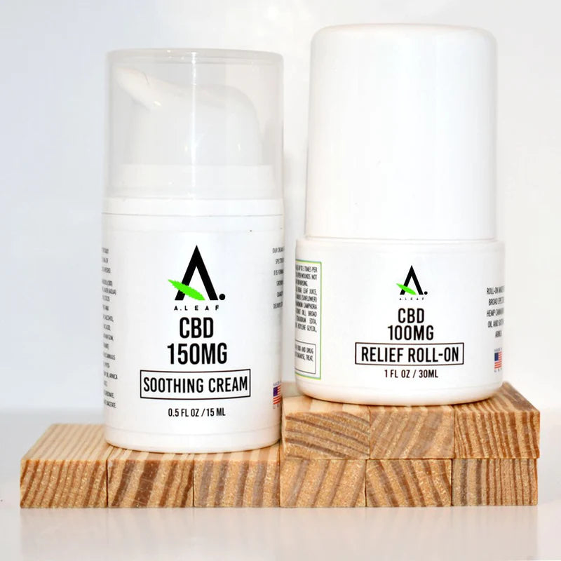 Two white A Leaf containers include a 0.5 fl oz Travel-Size Broad Spectrum CBD Soothing Cream (150mg) with pump and a 1 fl oz, 100mg CBD relief roll-on. Both are vegan, all-natural, with minimal text and American flag icons.