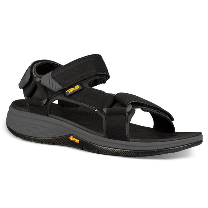 The Teva Mens Strata Universal Black sandal features adjustable Velcro straps, a rugged grey sole, and visible yellow Teva and Vibram logos—ideal for outdoor activities, comfort, and foot pain relief.