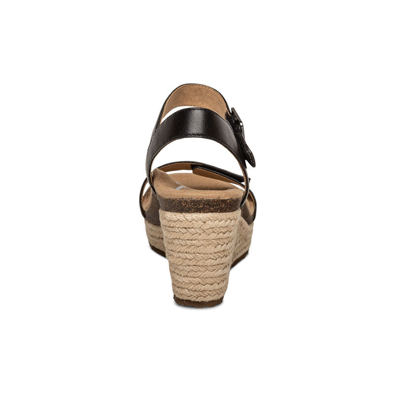Rear view of the Aetrex Womens Sydney Black Leather wedge sandal with woven rope platform heel, ankle strap, and buckle. Features memory foam footbed and arch support, shown centered against a white background.