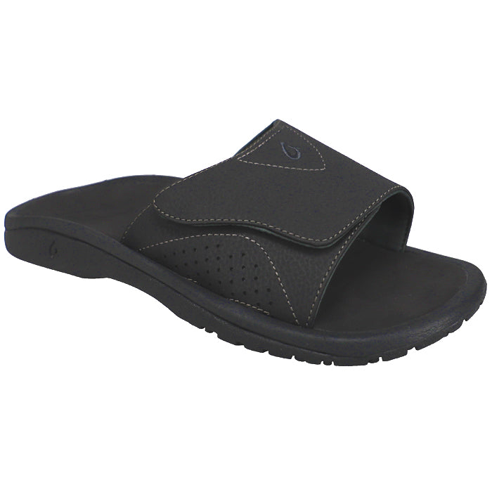 The OluKai Mens Nalu Slide Black/Black features a Wide adjustable strap with white stitching, subtle logo, contoured footbed for plantar fasciitis support, and a textured sole for extra grip.