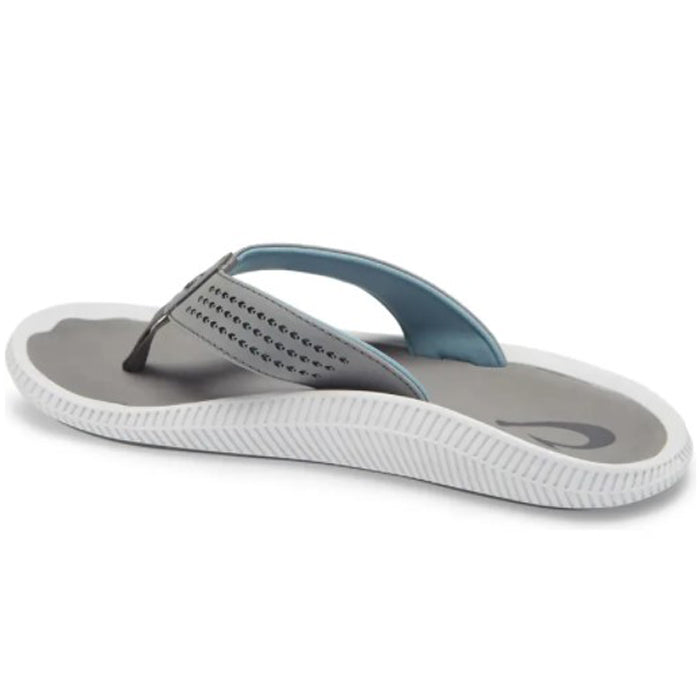 The OluKai Mens Ulele Stone/Stone sandal features a single gray flip-flop with light blue lining and a white textured sole, offering comfortable, water-friendly wear—ideal for any adventure.