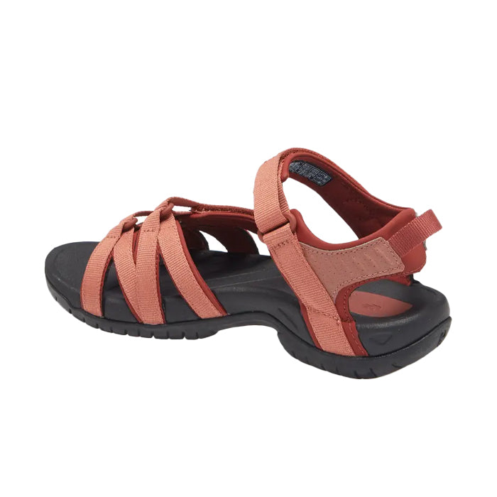 The Teva Womens Tirra Aragon sandal features a black sole, reddish-orange crisscross straps, open toe, arch support, and an adjustable ankle strap for sporty versatility.
