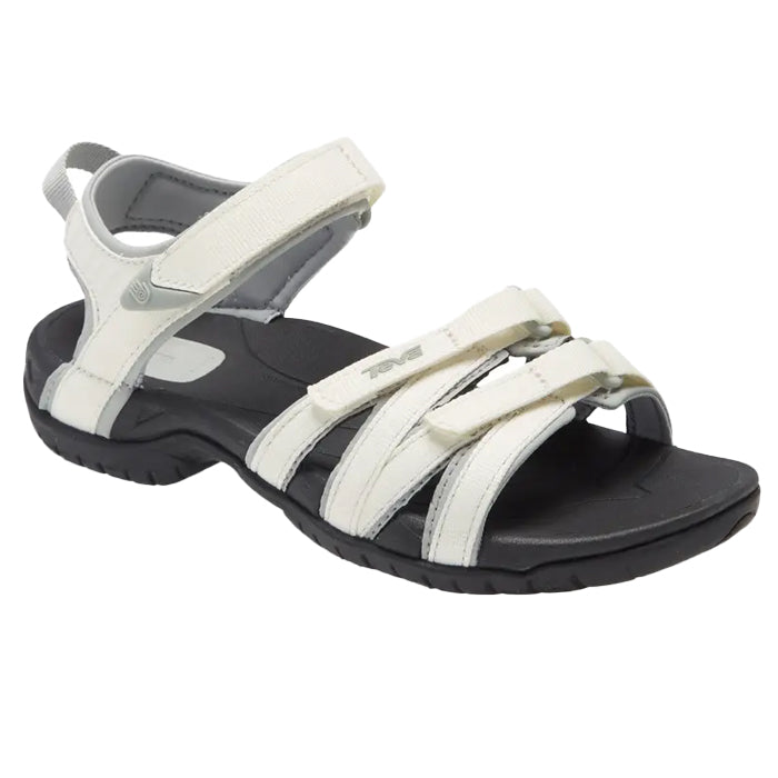 The Teva Womens Tirra White/Black by Teva is a versatile sandal with white straps, black sole with arch support, adjustable Velcro at ankle and toe, and a heel pull tab—ideal for outdoor or casual use.