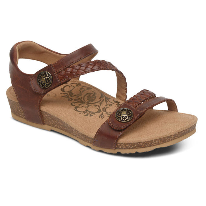 The Aetrex Womens Jillian Walnut sandal features a low wedge heel, walnut leather braided straps, metal buttons, adjustable fit, floral-patterned insole, and an orthotic footbed for comfort.