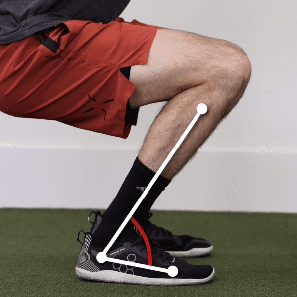 Close-up of a person performing a soleus stretch, with a white line graphic highlighting the angle of the shin and foot