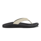 OLUKAI Women's Ohana Beige thong sandal, ecru strap over a contoured black footbed with arch support, angled view.