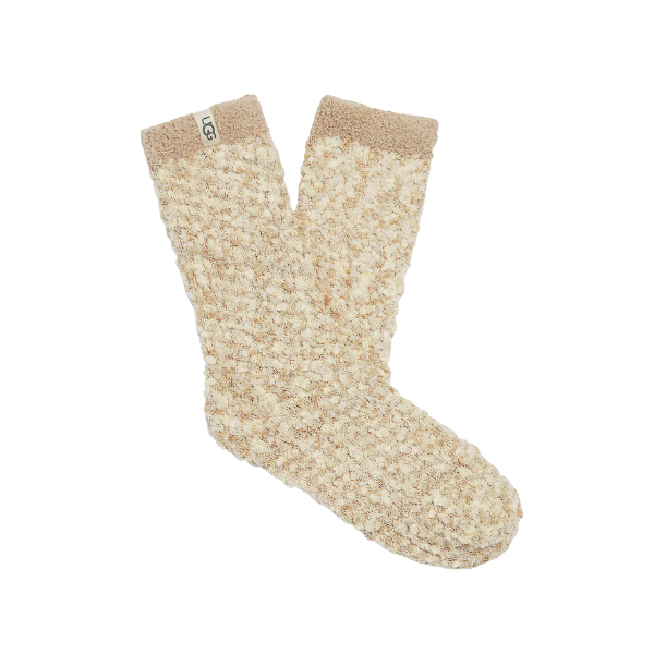 The UGG Women’s Cozy Chenille Sock in Cream features a textured, fuzzy chenille fabric with a small UGG logo tag by the cuff. The socks are shown laid flat on a white background.