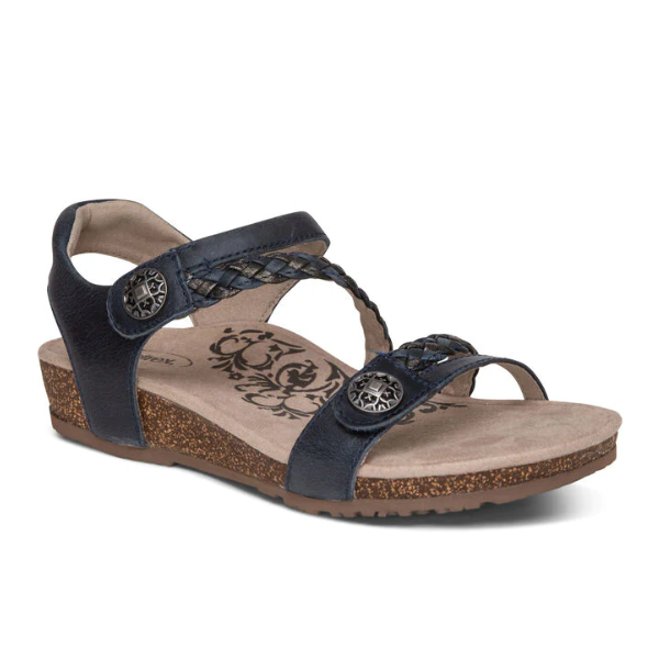 The Aetrex Womens Jillian Navy sandal features braided straps, metal button accents, a cork-textured sole, and a floral-patterned beige Lynco orthotic footbed.