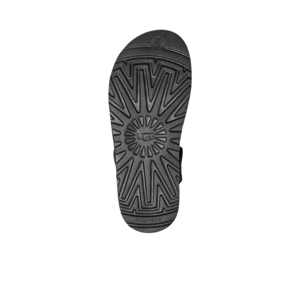 The image displays the black rubber sole of the UGG Womens Goldenstar Clog Black sandal, featuring geometric patterns and a central UGG logo on a plain white background that highlights its distinctive design.