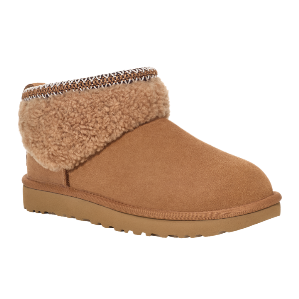 The UGG Women's Ultra Mini Maxi Chestnut is a tan suede ankle boot with a flat, textured outsole, a thick folded shearling cuff, and decorative top-edge stitching inspired by the cozy look of curly sheepskin boots.