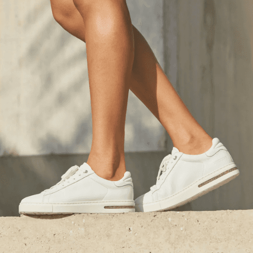 Person wearing white Birkenstock Bend Low leather sneakers with light-colored pants.