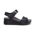 The Aetrex Women's Ariel Black by AETREX WORLDWide INC is a black platform sandal with an open toe, thick sole, ankle strap with silver buckle, and wide toe strap—ideal for foot pain relief, comfort, and style.
