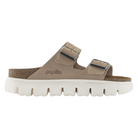The Birkenstock Womens Arizona Chunky Sand is a beige slip-on sandal with two adjustable buckle straps, a contoured footbed, and a thick white ridged sole. The BIRKENSTOCK brand name is printed on the side.