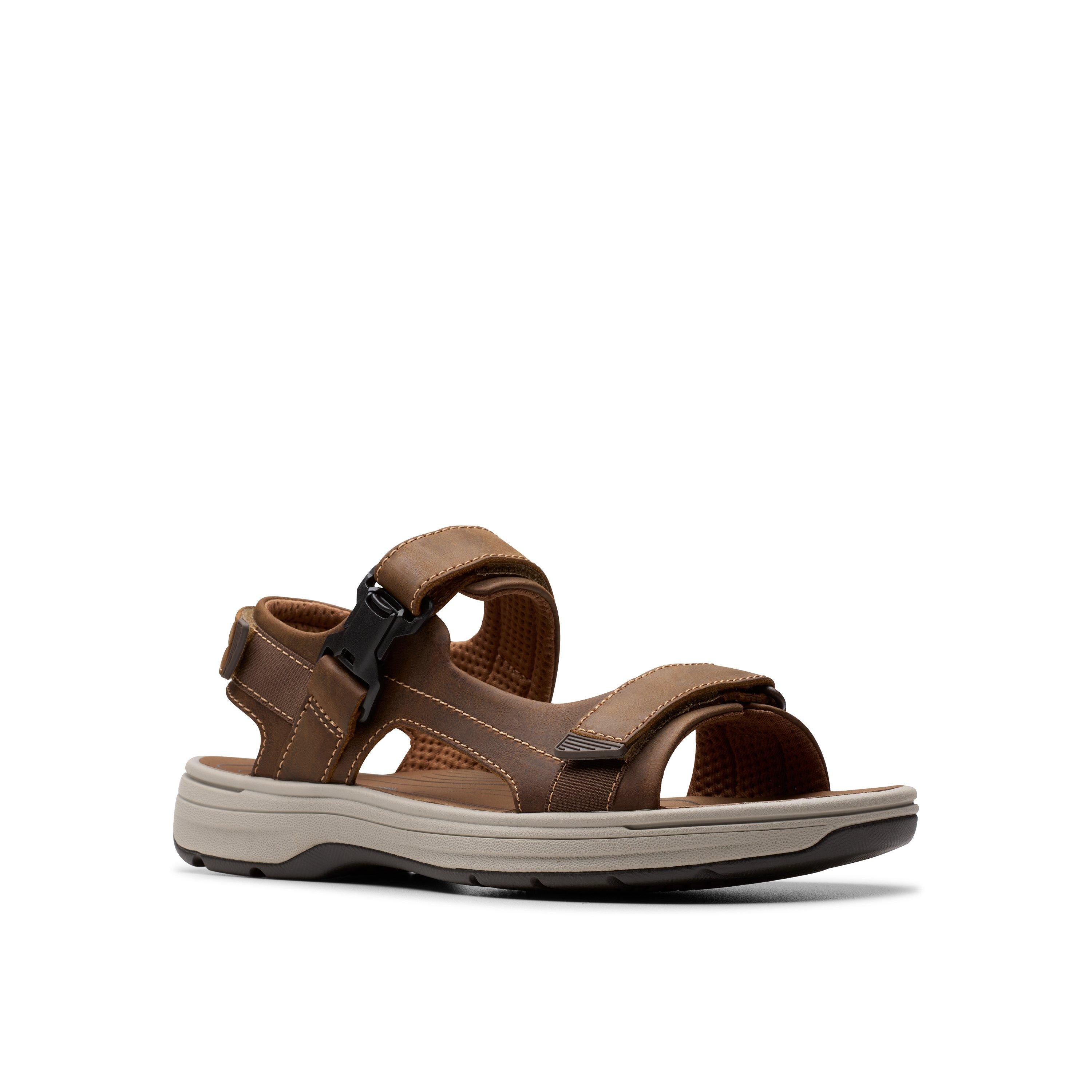 The CLARKS Clarks Mens Saltway Edge Wide Tan is a brown outdoor sandal with adjustable light tan leather straps, cushioned foam footbed, closed heel, and open toe design, shown against a white background.