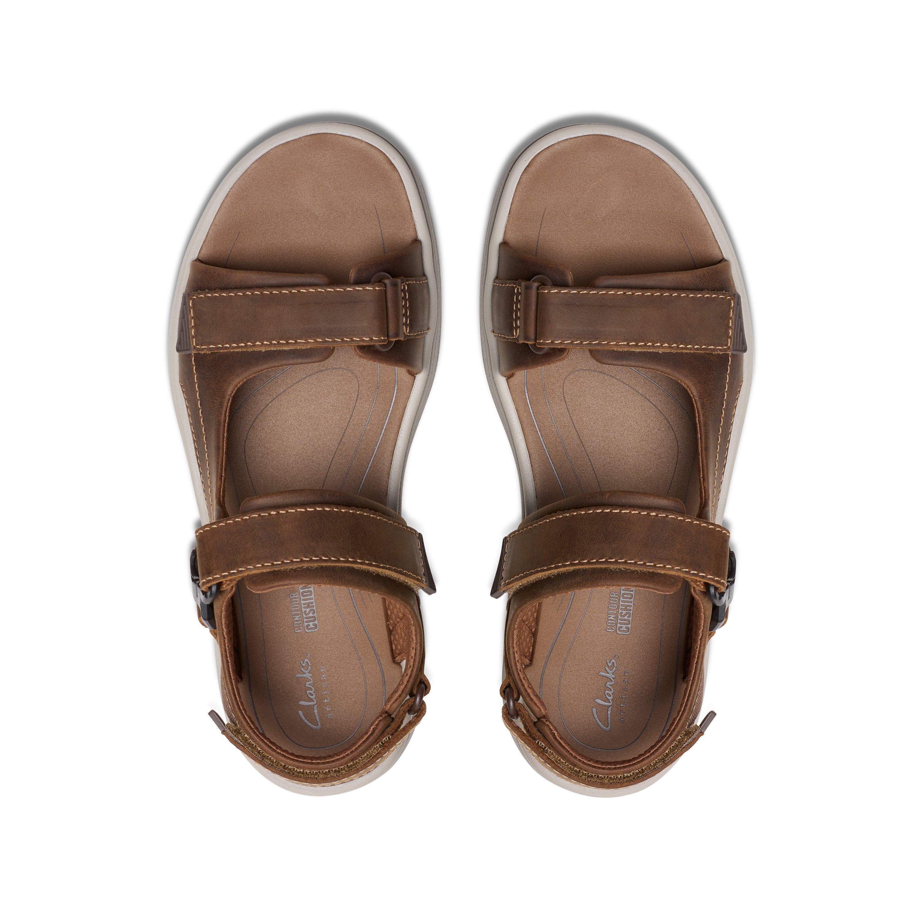 Top view of CLARKS Saltway Edge Wide Tan mens sandals, featuring light tan leather, adjustable straps, visible stitching, and a cushioned foam footbed, displayed side by side on a white background.