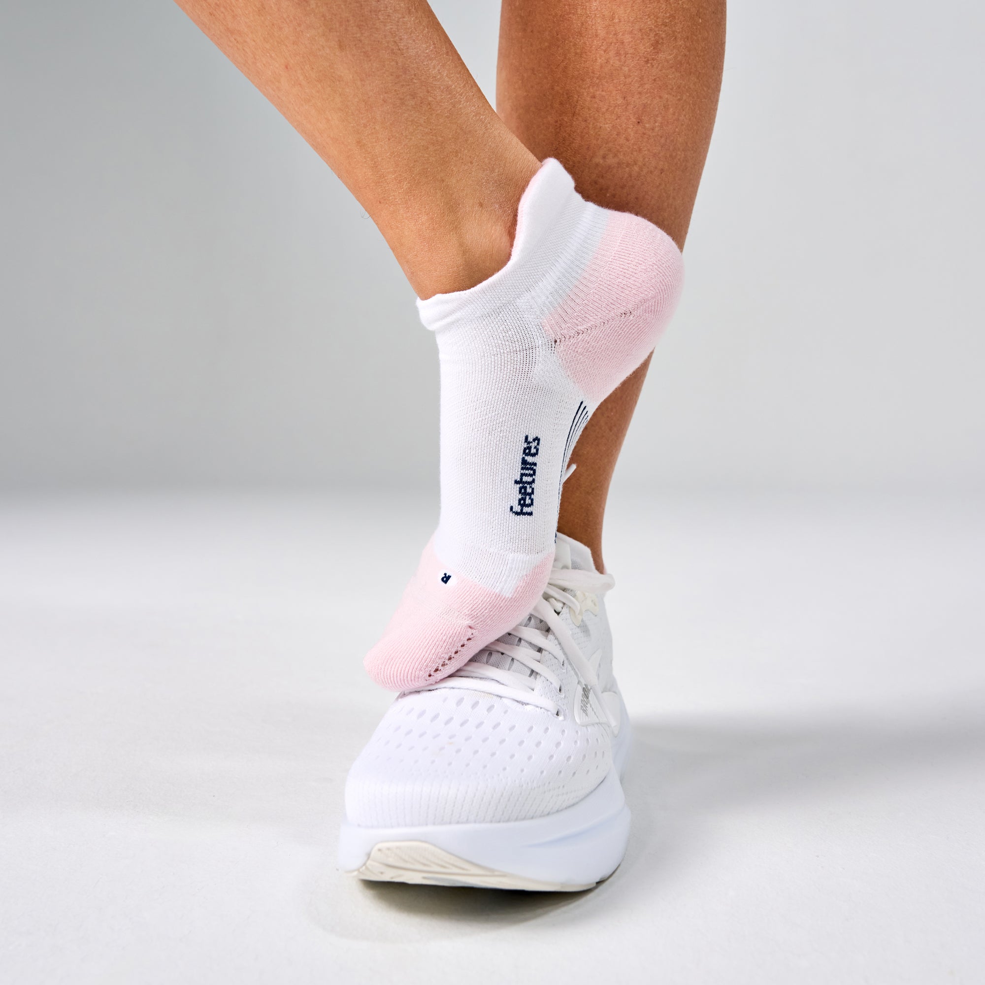 FEETURES Elite Max Cushion No Show Tab White Rose sock, cushioned footbed and blister tab, sole view.