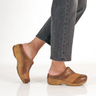 DANSKO Women's Zinnia Clog Tan Multi worn in a lifestyle setting, open-back clog with arch support.