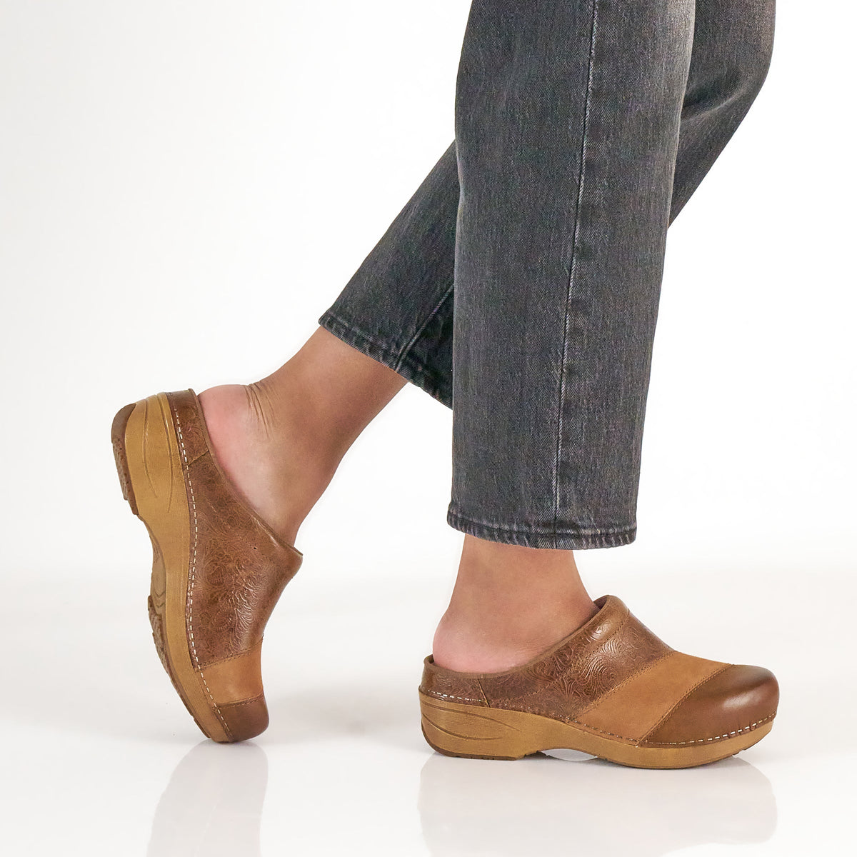 DANSKO Women's Zinnia Clog Tan Multi worn in a lifestyle setting, open-back clog with arch support.