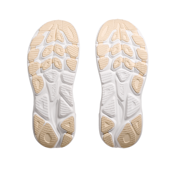Two black and gold HOKA Womens Clifton 10 running shoe soles display distinct geometric tread patterns for grip, shown from the bottom against a plain white background. These cushioned trainers are designed for comfort and performance.